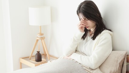 朝、ベッドで悩む女性
