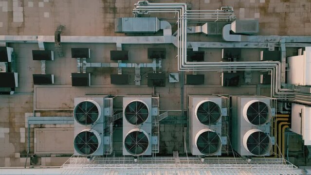 Ascending drone footage over a large industrial air conditioning system mounted on flat roof