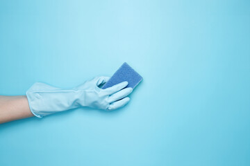 Womans hand in rubber glove holds yellow dishwashing sponge. House cleaning. Copy space