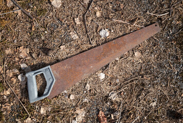 Rusty saw lying on the ground outdoors