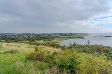 an expansive lake in the distance under a grey sky with some clouds