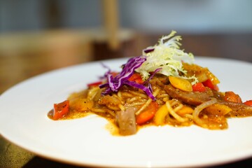 Close-up of a plate of freshly-cooked spaghetti pasta, topped with slices of seared beef tenderloin
