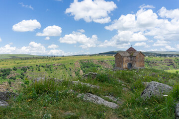 Brownstone church on the edge of a canyon in a green grass meadow.  Georgia