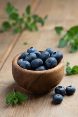 Close-up image of a wooden bowl filled with fresh blueberries