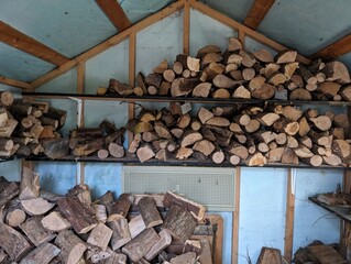 some shelves with firewood piled together in a room covered by wood