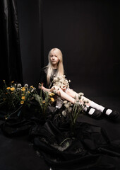 Portrait of a girl in studio on a black background with dandelions