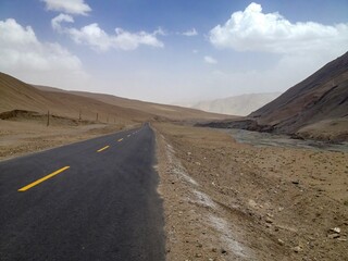 an empty road running through a desert valley near a mountain