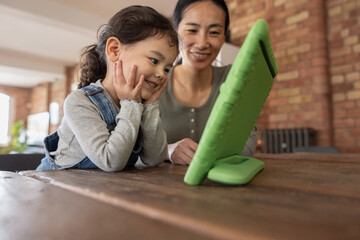Asian mother and daughter watching entertainment on digital tablet at home