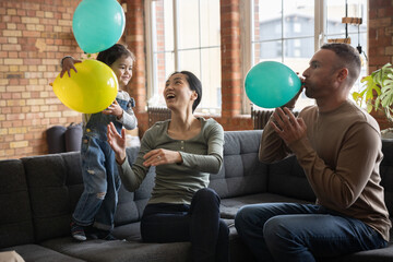 Family blowing up balloons to get ready for a celebration party 
