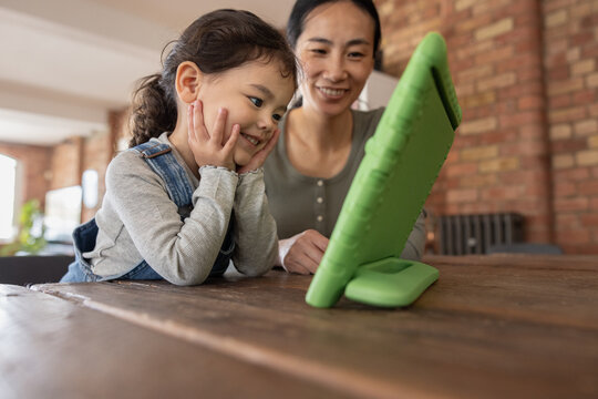 Asian mother and daughter watching entertainment on digital tablet at home