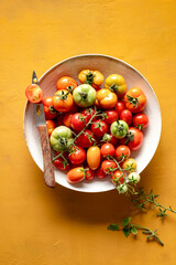 Group of cherry tomatoes in a plate, on a yellow background.
