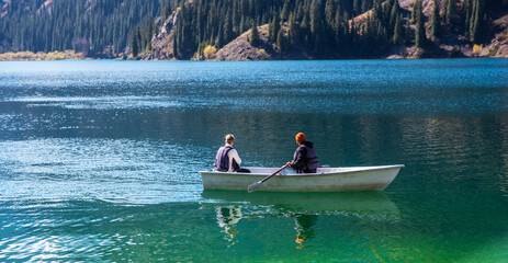 A view of lake and the beautiful mountain range in the background. Lovers ride in a boat on a lake....