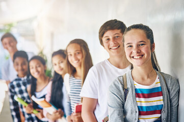 Teenager, friends and portrait on school campus or learning development, education or scholarship. Girls, boys and face in building hallway with books for student studying or together, group or smile