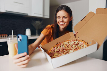 Woman capturing a delicious moment taking a photo of a pizza with her phone at a table
