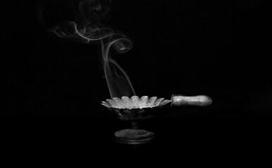 Incense smoke coming out of the burner on a black background
