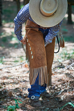 Cowgirl fastening chaps before riding
