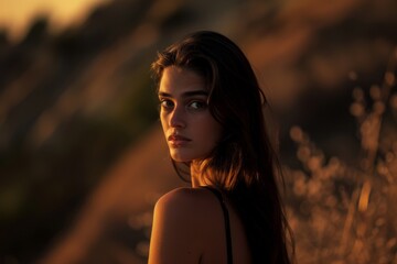 Portrait of a woman in a natural setting bathed in golden sunlight at sunset, with a calm and introspective expression.