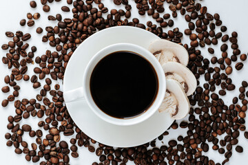 coffee beans are scattered on a light background, and in the center there is a coffee cup with a saucer, next to it in the saucer there are three slices of champignon mushroom. mushroom coffee shot fr