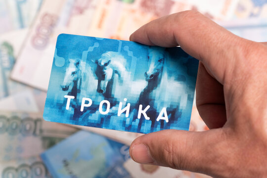 Kazakhstan May 15, 2024.Hand holds troika fare card against background Russian ruble banknotes.