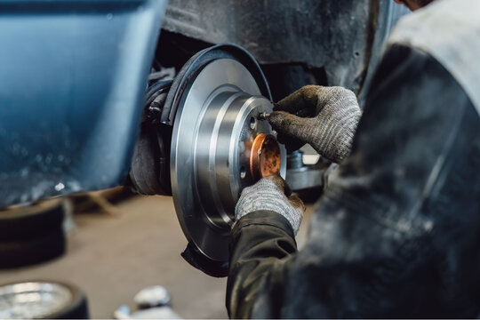 The rim is removed showing the rotor and caliper. Disc brake on car in process of new tire replacement