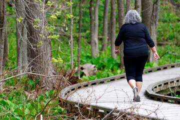 Femme âgée faisant du jogging sur un chemin en bois dans les bois