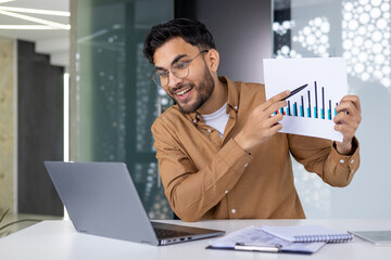 Happy man presenting business graphs during a video conference meeting in modern office