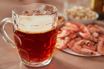 Beer in a glass and snacks next to it on the table, beer drinking traditions, close-up