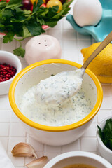 Greek yogurt sauce with lemon, garlic and parsley. Bowl with spoon in it full of sauce.