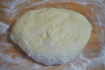 pizza dough on a wooden board with flour, prepared raw dough lies on a wooden board,, making a pie from the dough