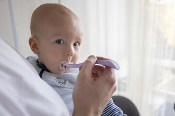 Father feeding his baby with yogurt at home. Feeding the baby in an upright position.