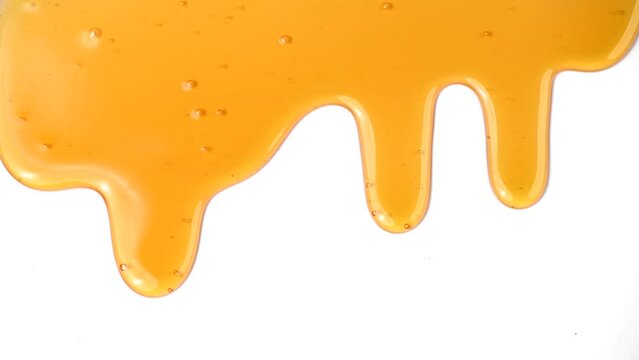 Honey dripping, pouring, flowing over white background. Close-up. Healthy organic liquid sweet sticky honey dipping, isolated on white, closeup. Slow motion 