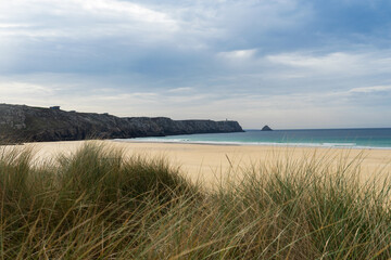 Derrière les hautes herbes de la plage de Pen Hat, le bleu de la mer d'Iroise contraste avec le...