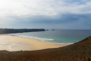La plage de Pen Hat se d&eacute;voile depuis les falaises, avec en arri&egrave;re-plan la majestueuse pointe de Pen Hir et le c&eacute;l&egrave;bre Tas de Pois, offrant une vue panoramique &eacute;poustouflante de la c&ocirc;te bretonne.