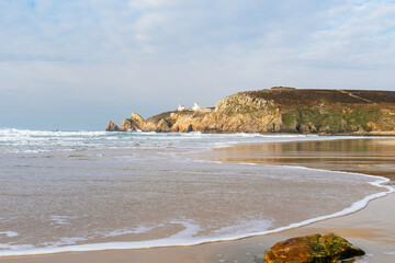 Le sable doré de Pen Hat, parsemé de rochers, rencontre les écumes de mer, avec en toile de fond les falaises imposantes de la pointe du Toulinguet.