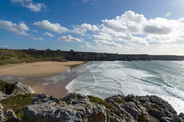 La plage de Pen Hat, sous un ciel bleu parsemé de nuages blancs, révèle ses étendues de sable et ses vagues couvertes d'écume sur la presqu'île de Crozon.