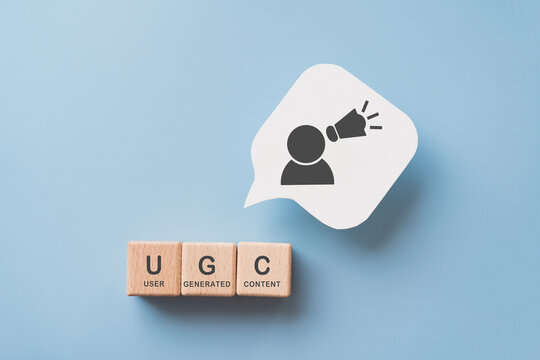 For user-generated content concept.(UGC) Online marketing. Customer create content on social media . Wooden cube blocks with "UGC" text and abbreviation , white speech bubble paper with icon