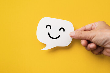 Hand hold happy face on real speech bubbles to each other. Giving good words to each other or giving positive feedback satisfaction from good customer feedback reviews