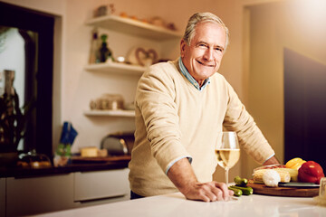 Senior man, happy and portrait with wine glass in kitchen for cooking, retirement and nutrition. Elderly male person, wellness and alcohol with vegetables for salad, food and vegan diet in apartment