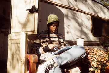 n enchanting lady exudes bohemian vibes against the park scenery, with a trailer in the background.