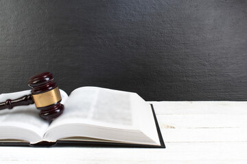 Law concept - Open law book with a wooden judges gavel on table in a courtroom or law enforcement...