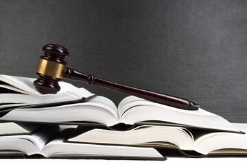 Law concept - Open law book with a wooden judges gavel on table in a courtroom or law enforcement...