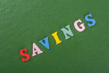 SAVINGS word on green background composed from colorful abc alphabet block wooden letters, copy...