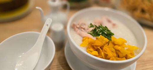 rice porridge with shredded chicken called bubur ayam served with crackers and sliced spring onion and others condiments