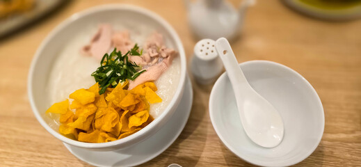 rice porridge with shredded chicken called bubur ayam served with crackers and sliced spring onion and others condiments