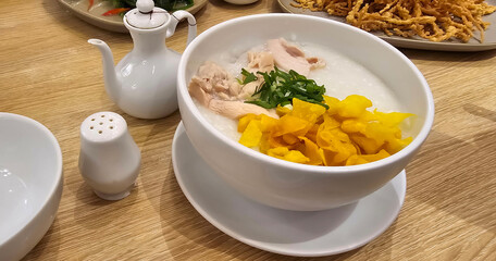 rice porridge with shredded chicken called bubur ayam served with crackers and sliced spring onion and others condiments