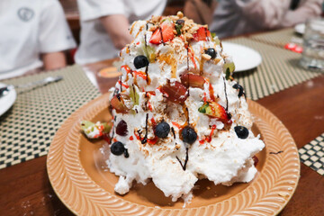 baked Alaska, a swiss desert with cream, ice cream, cake and fruit. Fire is burning on the outside layer taken in a restaurant