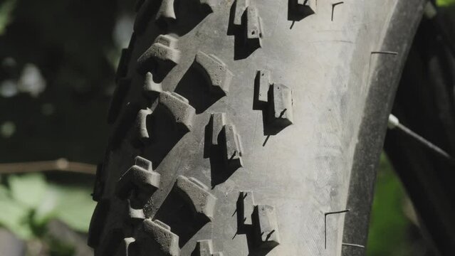 Bicycle rubber tire treads on wheels close-up on natural forest background - footage for cycling tourism. Dirty bike tires of fat-bike.