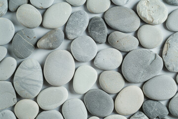 Round gray flat beach pebbles laying on white background, up view photo