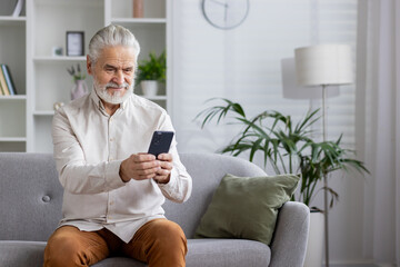 Senior man using smartphone in living room for social media and communication
