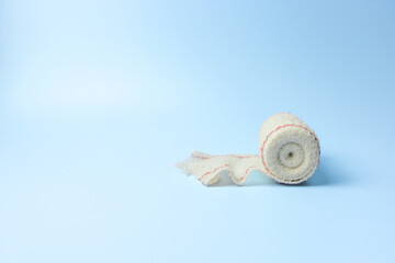 A white bandage is laying on a blue background. The bandage is frayed and torn, giving the...